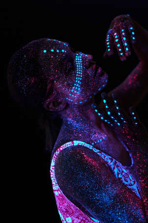 Art girl cosmos in ultraviolet light. Woman does yoga, body warm-up. Entire body is covered with colored droplets. Astral yoga. Noise, out of focusの写真素材