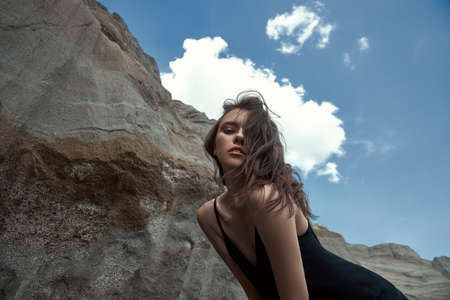 Fashion sexy woman in a suit posing on sand rocks. Modern independent girl, beautiful makeupの写真素材