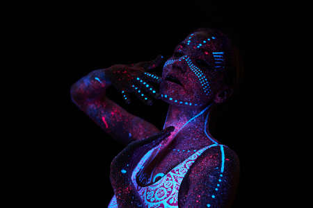 Art woman cosmos in ultraviolet light. Entire body is covered with colored droplets. Girl posing in...