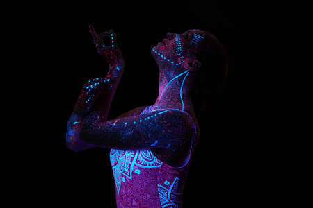 Art woman cosmos in ultraviolet light. Entire body is covered with colored droplets. Girl posing in...