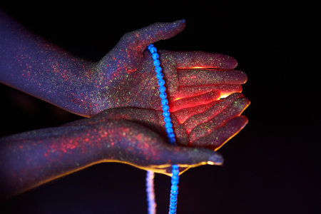 Rosary in hand, prayer. Light through the palms of your hands in ultraviolet, God and religion,...