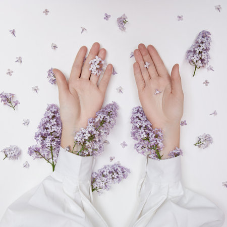 Natural woman cosmetics for hands made of lilac flowers and petals. Moisturize and soften the skin of the hands. Lilac flowers protrude from the sleeves of the armの写真素材