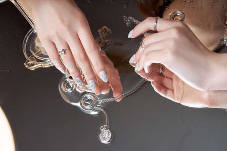 Beauty portrait of a woman with natural makeup and painted polished nails on her hand. Rings on the fingers of the handの写真素材
