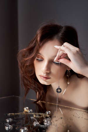 Woman holds a glass glass in her beauty hand. Rings and jewelry on table, luxurious life. Alcoholismの写真素材
