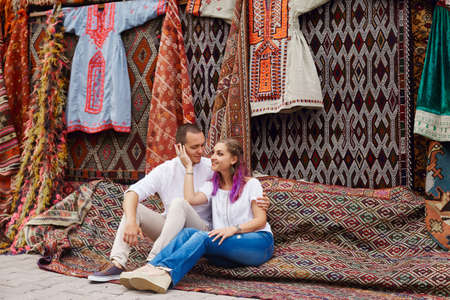 Couple in love buys a carpet and handmade textiles at an oriental market in Turkey. Hugs and...