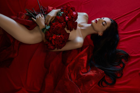 Beautiful sexy brunette with a bouquet of red roses lying on the floor, naked body parts,   portrait of a womanの写真素材