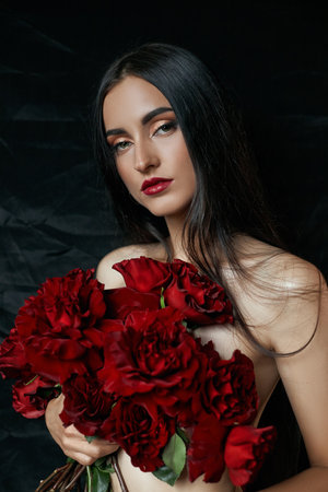 Beautiful sexy brunette with a bouquet of red roses lying on the floorの写真素材