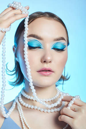 Romantic woman with pink hair in a blue beret on her head, a French woman with a rose in her hands. Blue makeup on the eyes eyelids of a young womanの写真素材