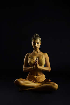 Yoga woman gold body, spiritual and physical practices. Judaism exercises body and soul. Fitness woman yoga. Healthy life and natural balance between body and mental development. black backgroundの写真素材