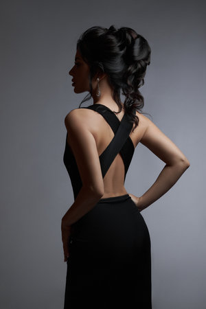 Beauty portrait of a woman with black hair, beautiful makeup. Long hair with styling, romantic woman on a gray backgroundの写真素材
