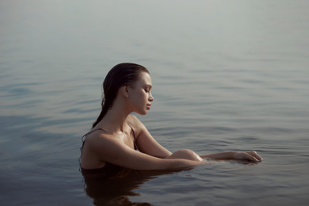 Beautiful romantic woman sitting near a pond lake. Wet woman in her underwear in the rays of the sun at sunset. natural beauty long hairの写真素材