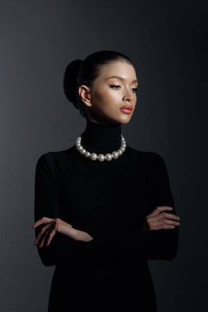 Woman poses confidently, dressed in a stylish black turtleneck and exquisite luxury jewelry. Hair pulled back in a bun, natural cosmetics and make-upの写真素材