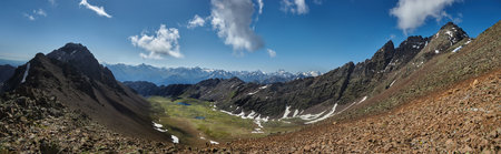 Vibrant green valley nestled between towering mountains showcases natural beauty under a clear blue...