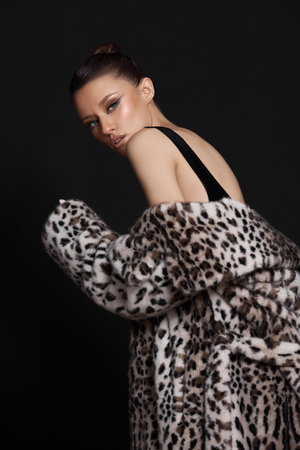 Indoor studio photoshoot features a stylish model wearing a leopard print coat. model poses...