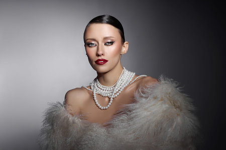 Beauty fashion model poses in a studio wearing a pearl necklace and a fur wrap. lighting highlights...