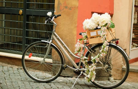 Bicycle with many white flowers near wallの写真素材
