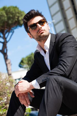 Confident handsome man with sunglasses sitting outdoor.の写真素材