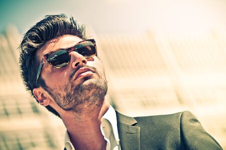 Handsome businessman with sunglasses, outdoor in the city. Intense lights.