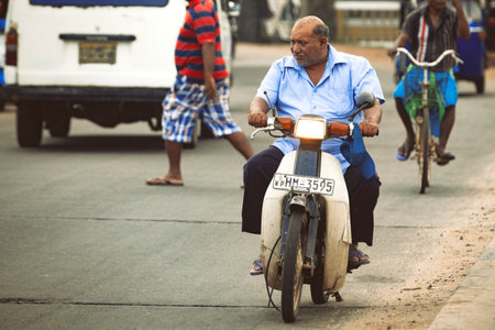 Negombo, Sri Lanka. July 20, 2016: A man is driving a scooter in the street. Negombo a town near the capital Colombo in Sri Lanka.のeditorial素材