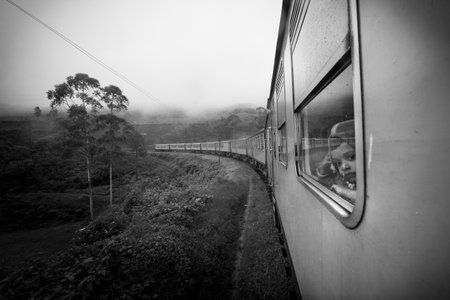 Nuwara Eliya, Sri Lanka. July 26, 2016: A child looks out the window inside the train that crosses the nature and plantations of tea in Nuwara Eliya in Sri Lanka. Black and white.のeditorial素材