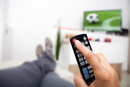 Turning off the TV. Remote control in hand. Man lying watching football and turning off the TV.