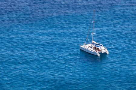 Catamaran boat white color in the middle of the blue sea by day. Small waves. Copy space on the...