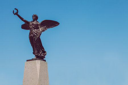 Winged victory statue. Monument to the war dead of the first world war. Winged angel with laurel in hand. Cloudless blue sky in the background.のeditorial素材
