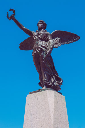 Winged victory statue. Monument to the war dead of the first world war. Winged angel with laurel in hand. Cloudless blue sky in the background.のeditorial素材