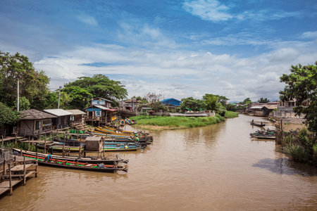 Canton de Nyaungshwe, Myanmar. July 31, 2019: Inle Boat Station in Inle Nyaung Shwe Canal. A series of fishing boats along the river generated by Inle Lake. Homes in the background.のeditorial素材