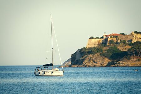 Sea with sailboat. Elba Island in Italy. Lighthouse on the rock of Porto Azzurro.の写真素材