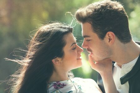 Young couple loving outdoors in a park. A young man and young woman embracing e kissing with passion...