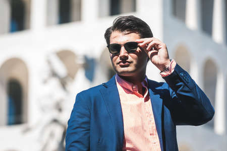 Business man with sunglasses. He blue jacket and shirt. In the background a building.の写真素材