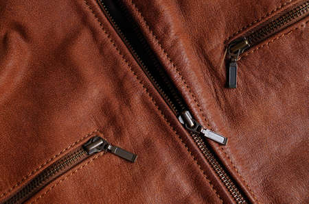 Main zipper and front pockets zippers of a brown leather jacket, showing nylon seamsの写真素材
