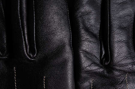 Close up of a pair of black leather gloves, one on top of the other, showing detailの写真素材