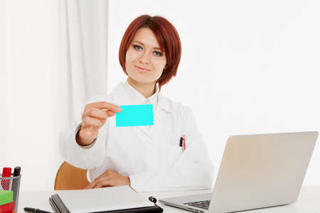 Doctor sitting behind her desk, on white backgroundの写真素材