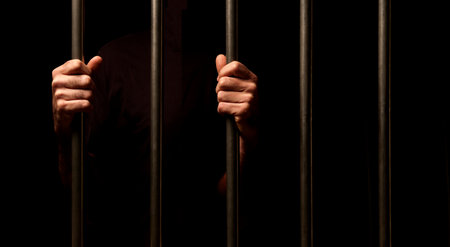 Man in jail holding a metal lattice on a black background.