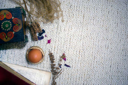 Easter flatlay composition with negative space, an egg, dry flowers and petals, wooden box and books on white backgroundの写真素材