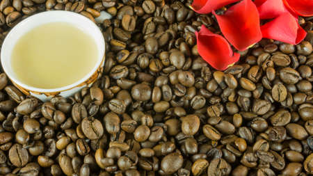 Fresh roasted coffee beans with a cup of coffee and rose leavesの写真素材