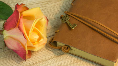 A book with key and a rose on a wooden table