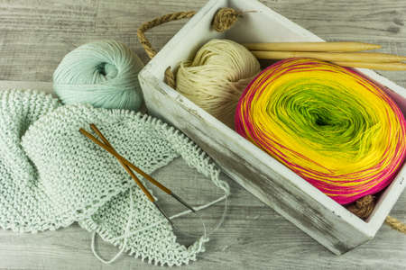 Various colors Wool balls in a wooden box with knitting needles on wooden tableの写真素材