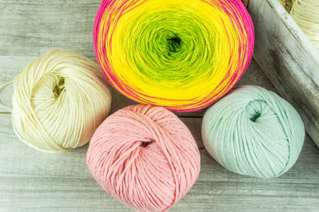 Wool balls in different colors with knitting needles on a wooden tableの写真素材