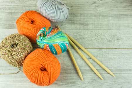 Wool balls in different colors with knitting needles on a wooden tableの写真素材
