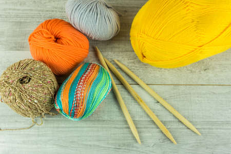 Wool balls in different colors with knitting needles on a wooden tableの写真素材