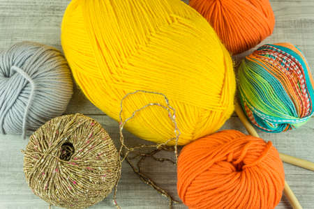 Wool balls in different colors with knitting needles on a wooden tableの写真素材