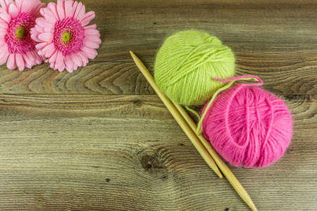 Colored wool balls with needles and a flower on a rustic wooden tableの写真素材
