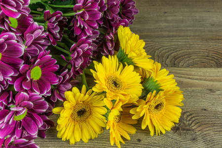 Colored gerbera flowers on a rustic wooden table as a backgroundの写真素材