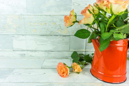 Red coffeepot with a bouquet of roses on a rustic white wooden backgroundの写真素材