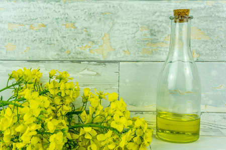 Rapeseed flowers with a bottle of rapeseed oil on a rustic wooden table