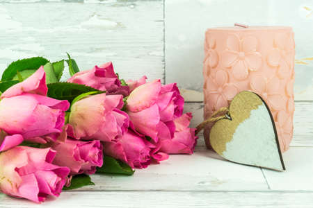 Red roses with a candle on a rustic wooden tableの写真素材