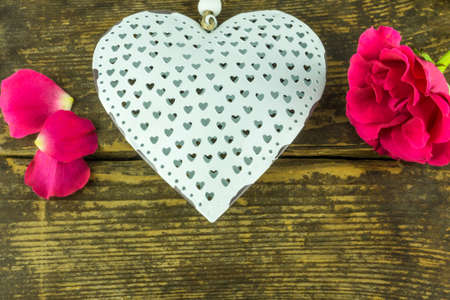 Red roses with a white heart on a rustic wooden tableの写真素材